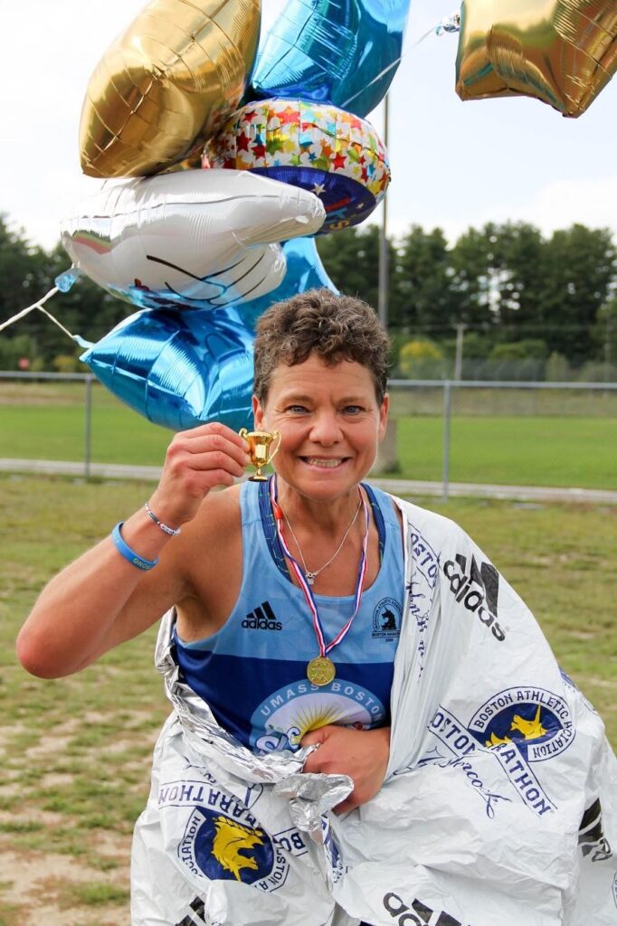 Amanda holding a tiny winners cup toy prize after finishing her virtual Boston Marathon.