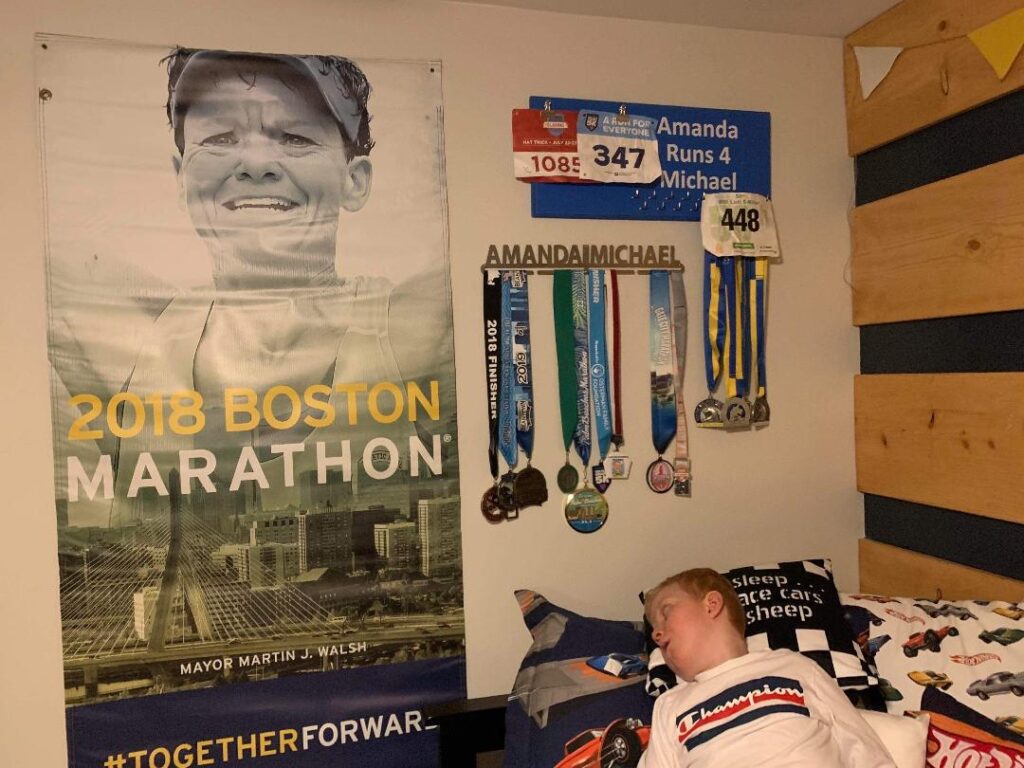 Michael at home with a poster of Amanda and the medals she has sent him on the wall.