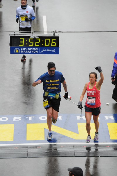 Randy finishing his first Boston in 2015 guided by Christine Houde, both with triumphant fists in the air!